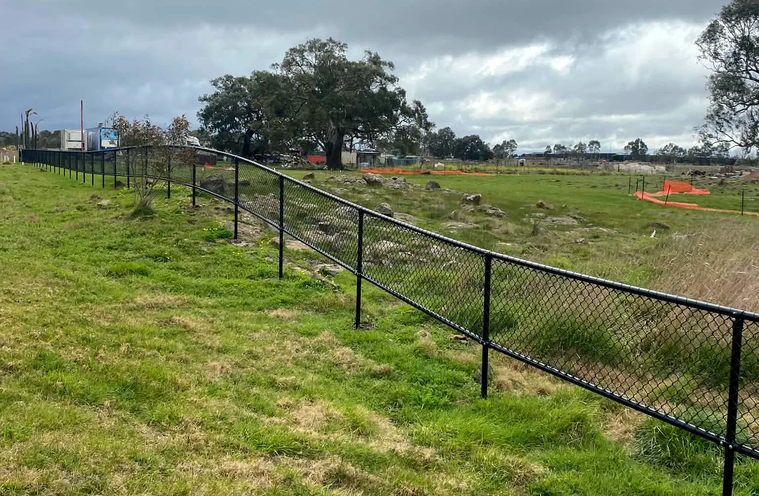 Long black perimeter fence across an open site