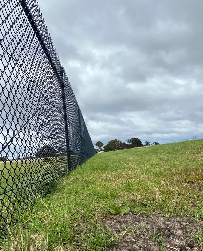 Close view along a newly installed black chain-mesh fence