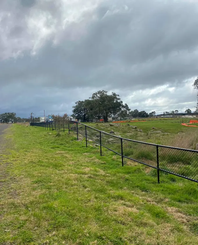 Long black perimeter fence crossing gently sloping ground
