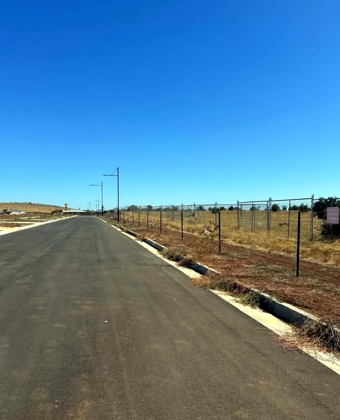 Long rural wire-mesh fence installed on steel posts beside a road