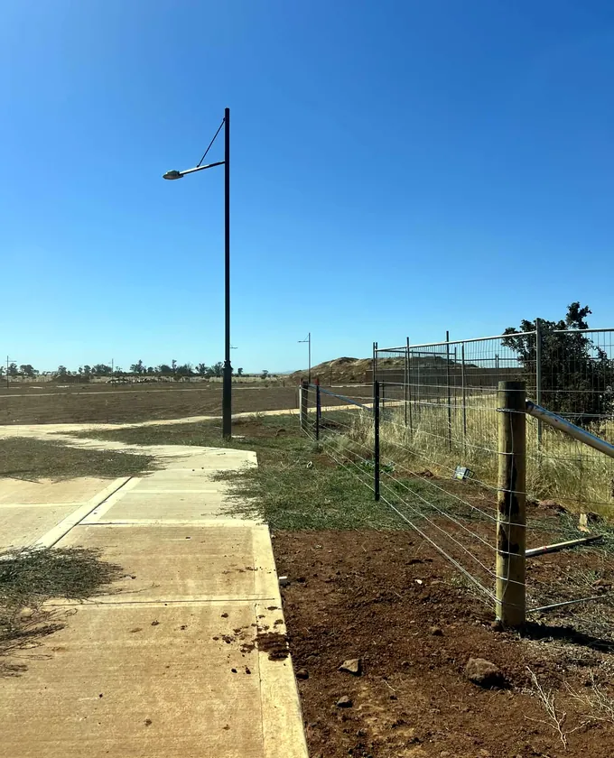 Timber strainer post, wire mesh and farm gate at a rural boundary