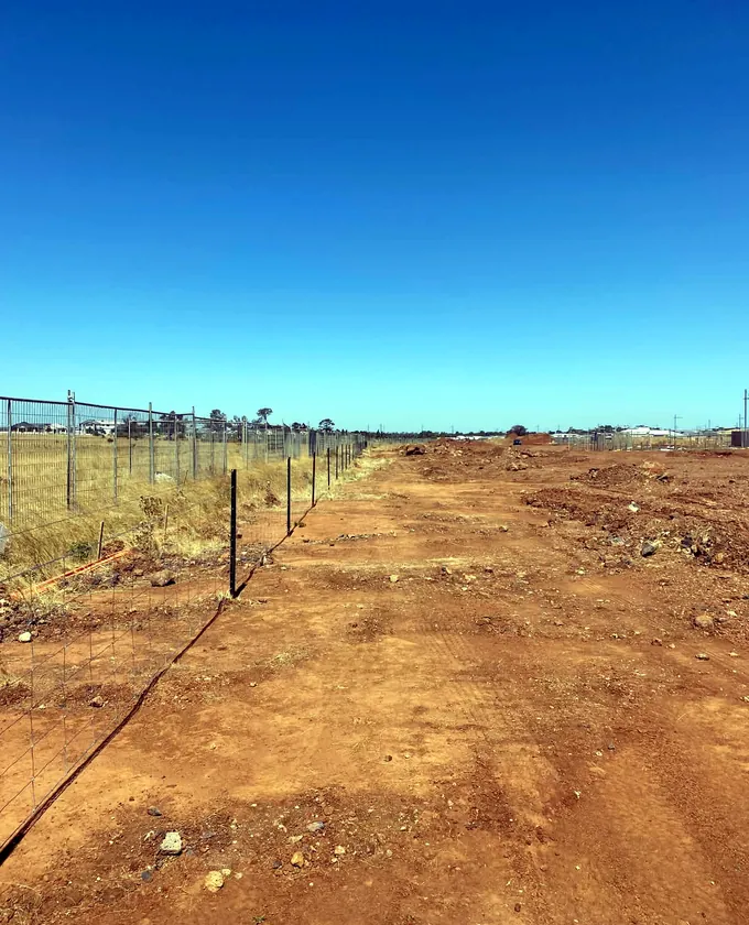 Rural wire fence being installed across open ground on steel posts