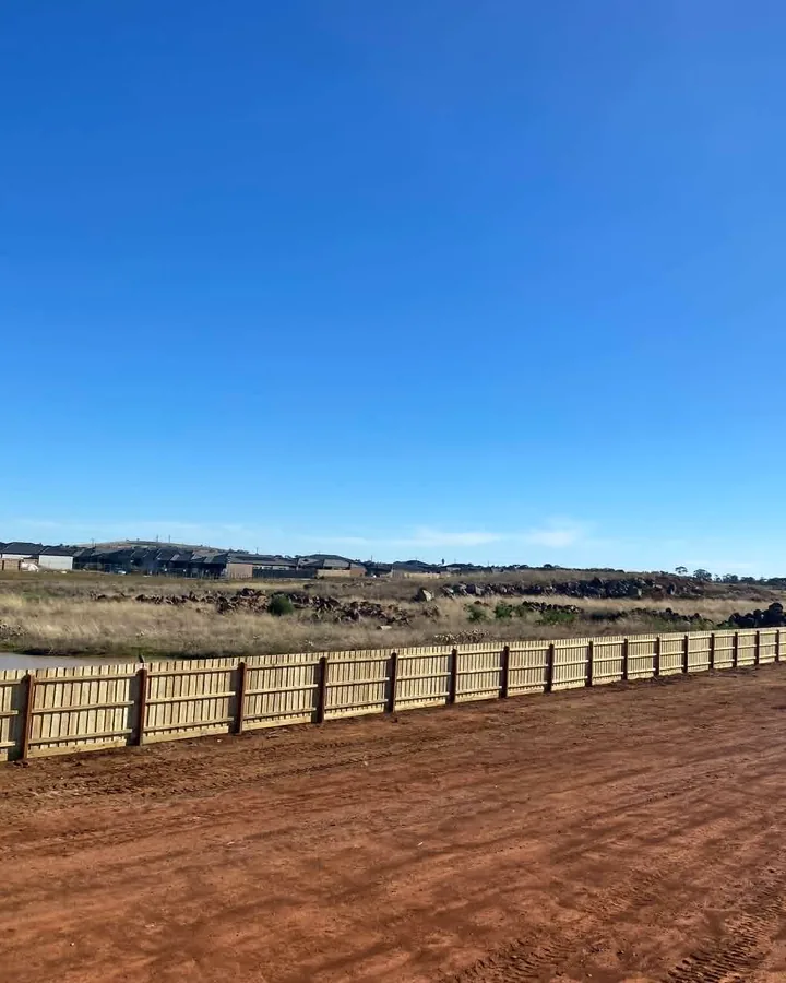 Long natural timber fence extending across a new subdivision site