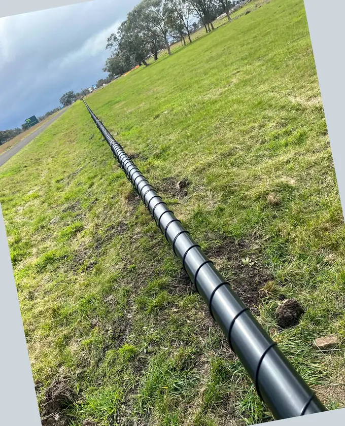 Close perspective along a black tubular fence top rail